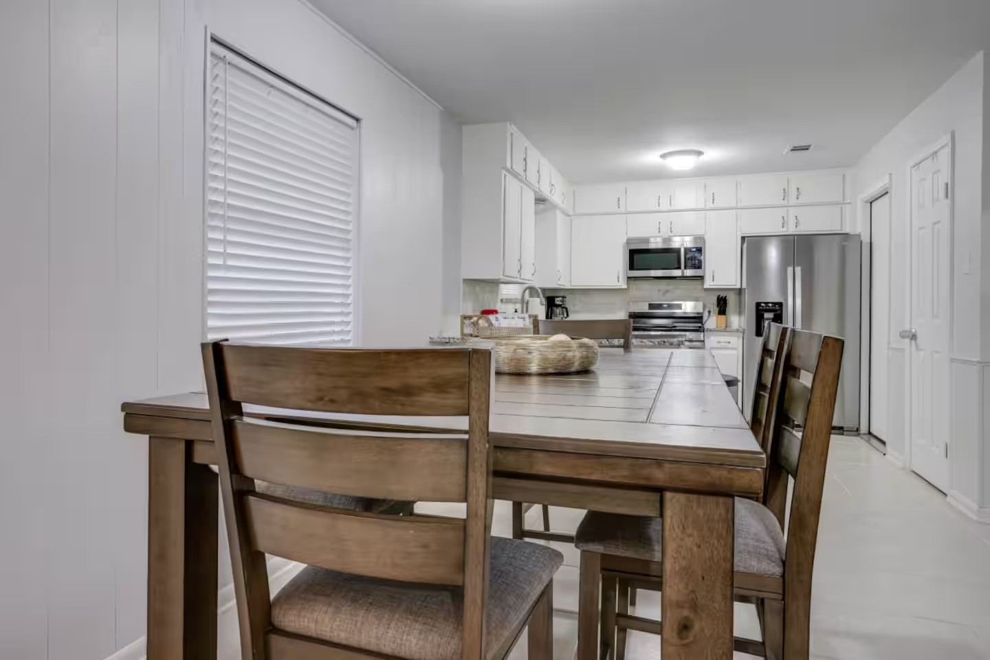 Kitchen and dining area with a wooden table, white cabinets, and stainless steel appliances.