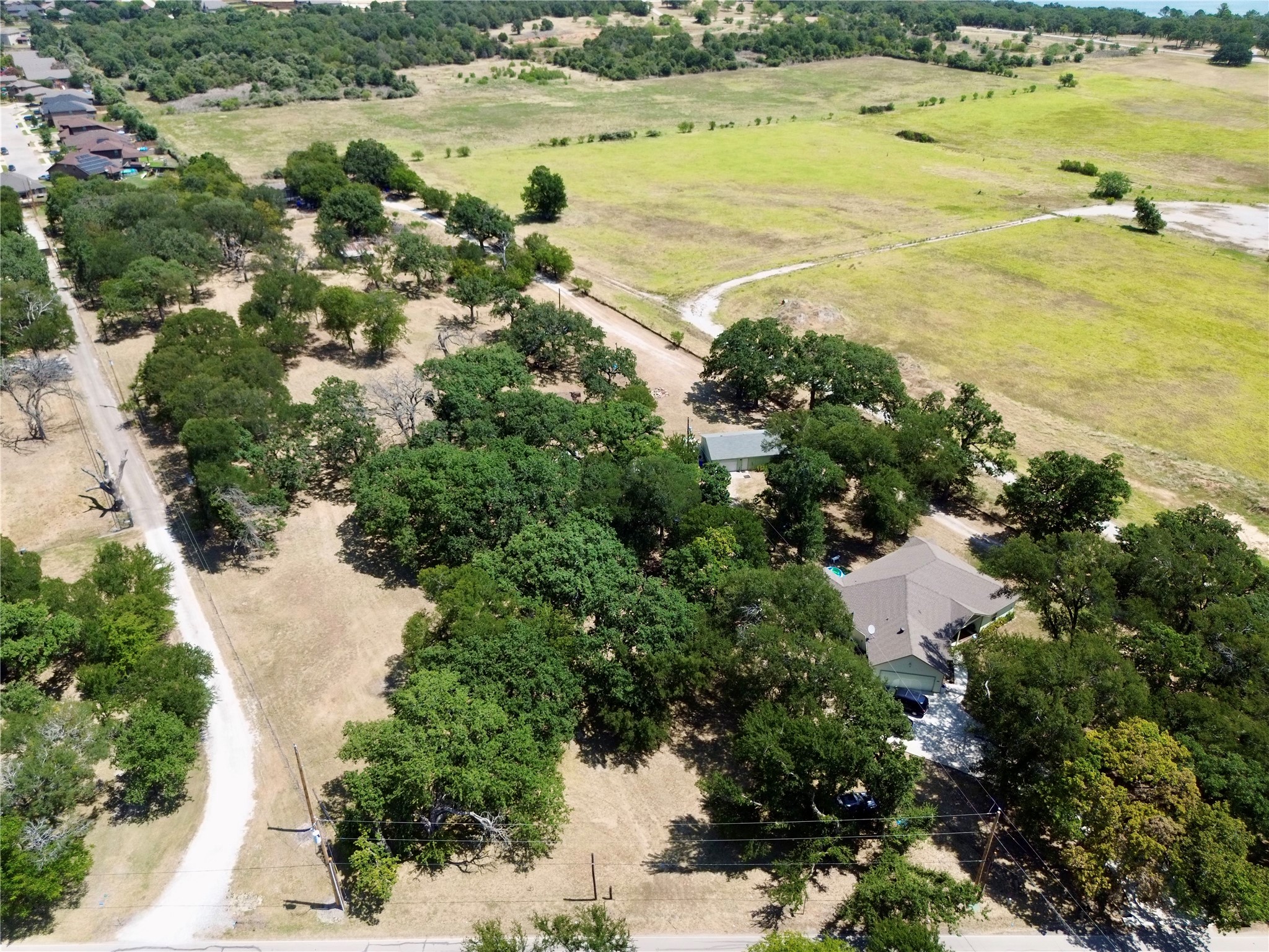Aerial view of a tree-covered property with a house and broad open land.