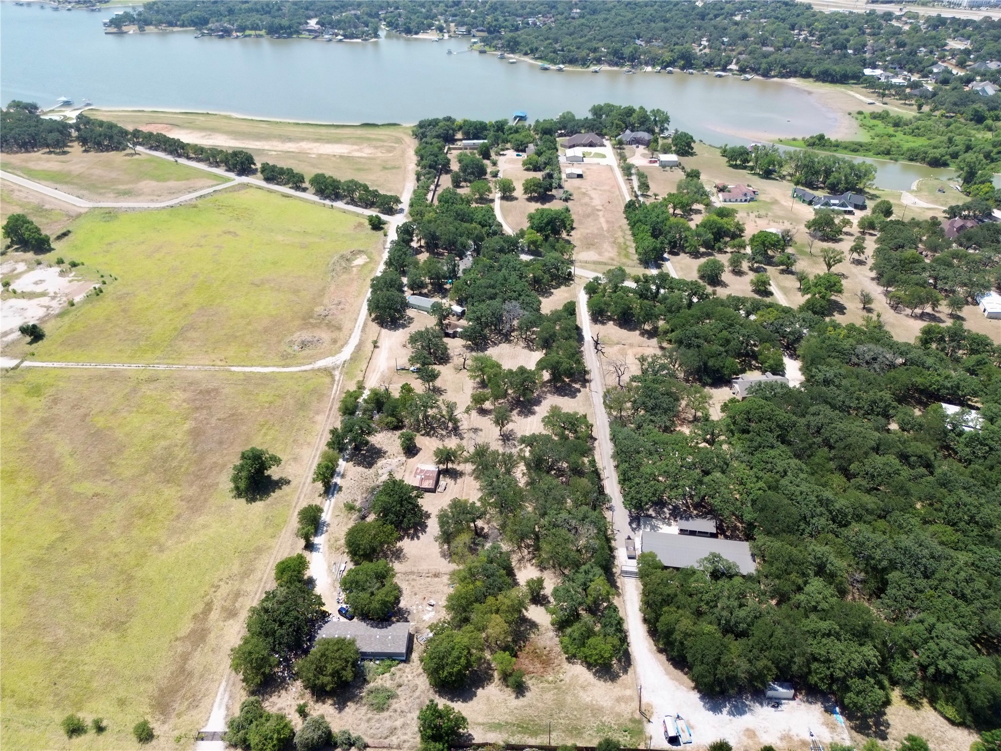 Aerial view of open fields and tree-covered acreage beside a lake.