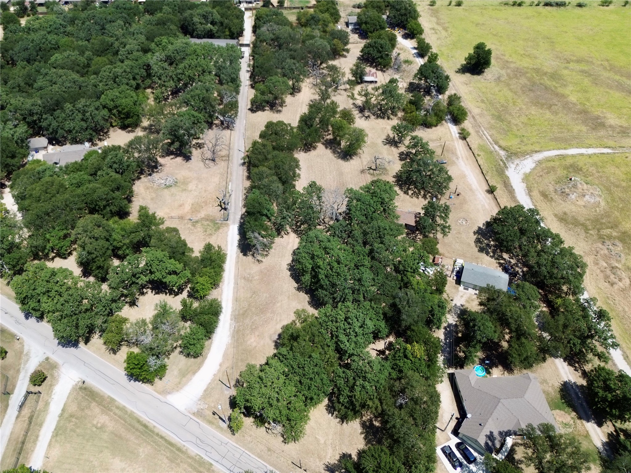 Aerial view of a spacious, tree-covered property with a house and long driveway.