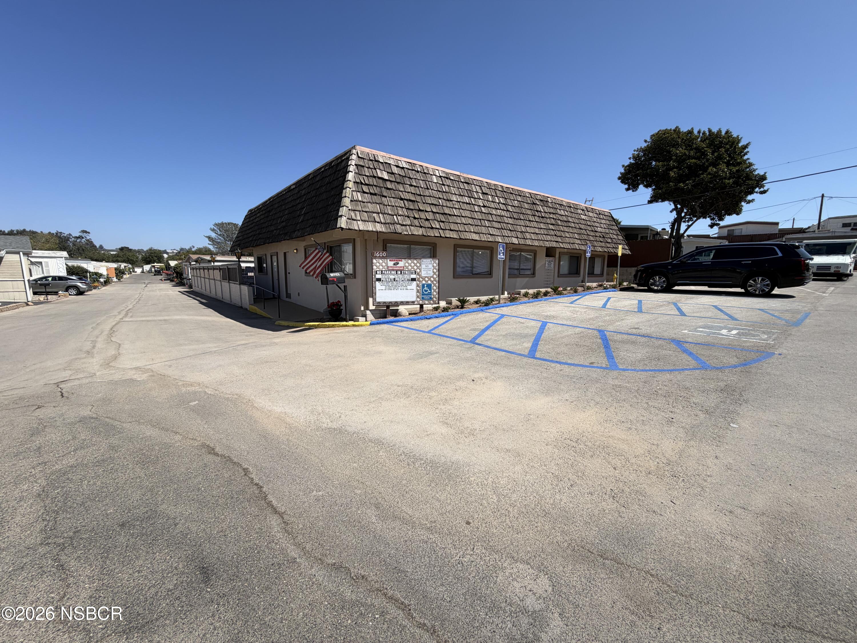 Community office with a steep shingled roof, American flag, and blue-striped accessible parking.