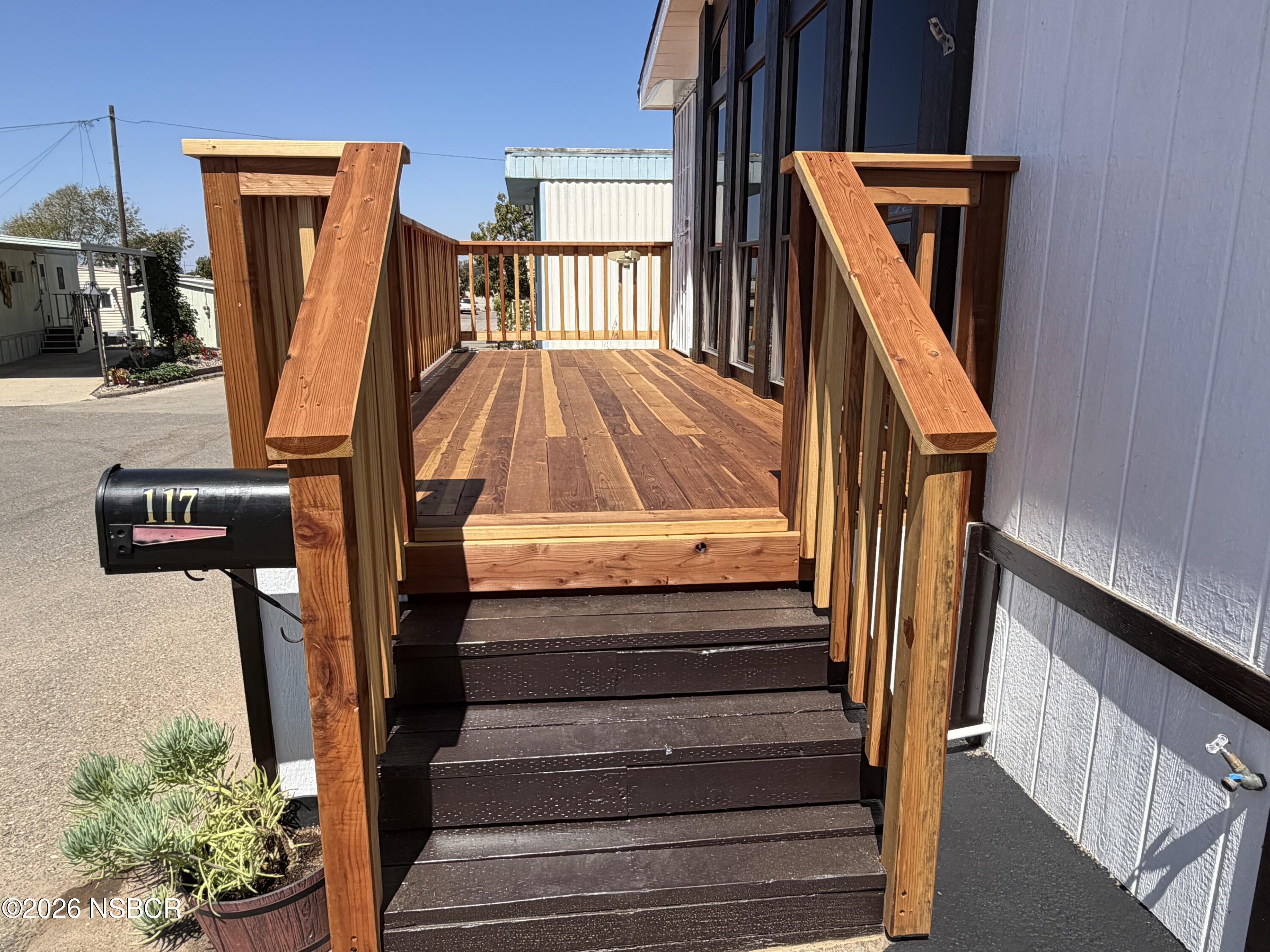 Wooden entry stairs lead to a raised deck beside the home, with a mailbox marked 117.