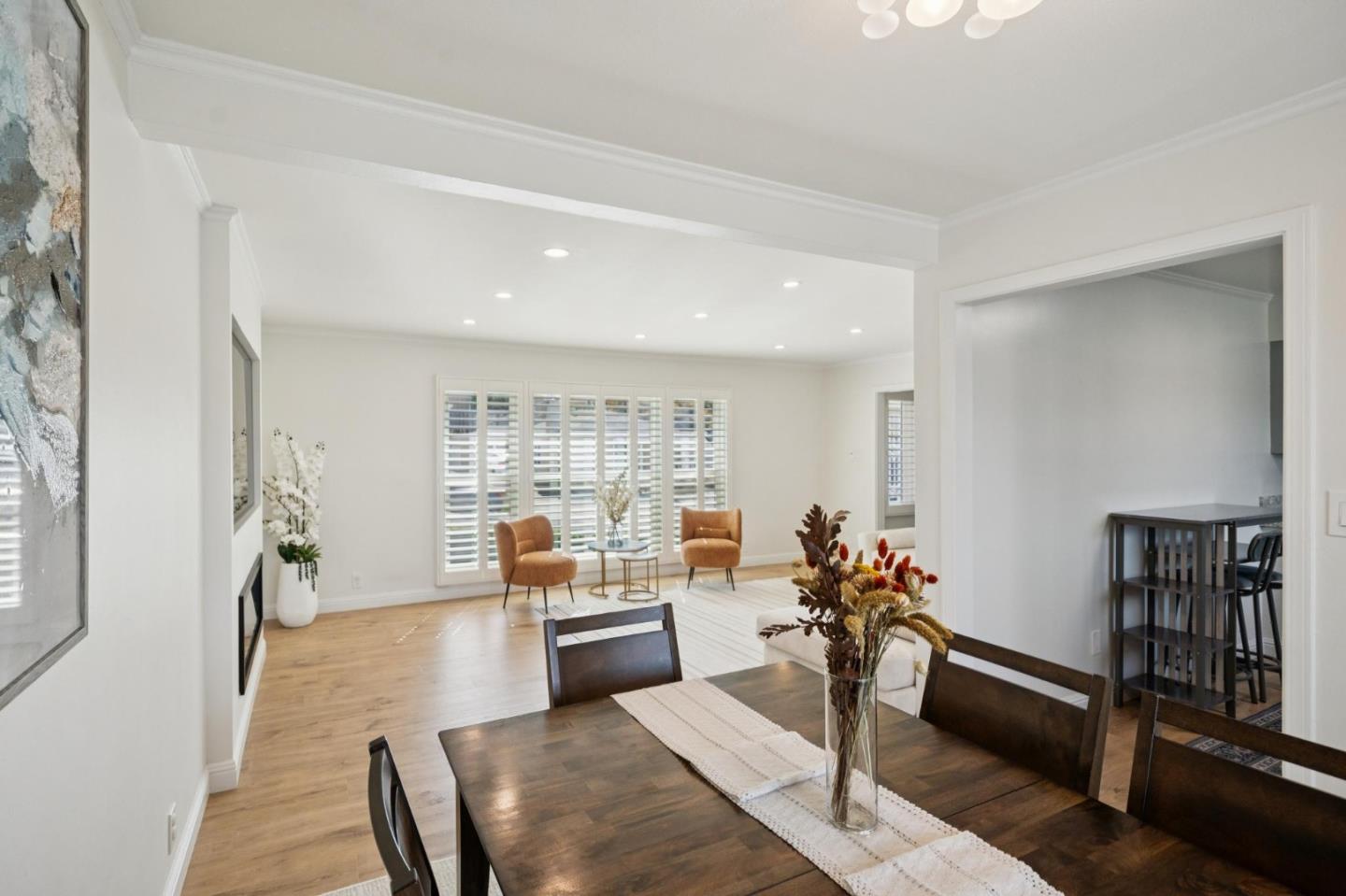 Dining area opening into a bright living room with plantation shutters and hardwood floors.