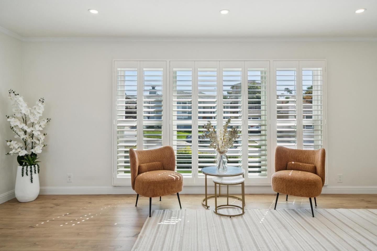 Sitting area with rust-colored armchairs and wide plantation-shuttered windows.