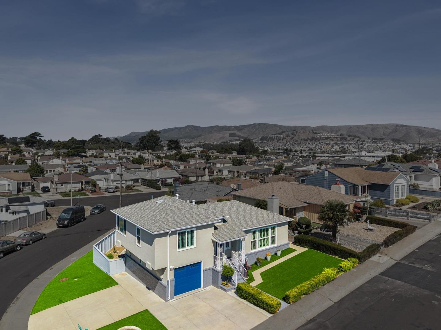 Aerial view of the home at 214 Manor Drive, with a blue garage door and bright green lawn.