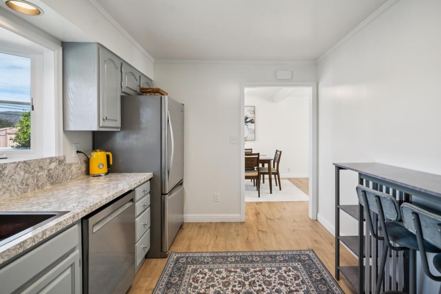 Kitchen with gray cabinets, stainless steel appliances, stone counters, and a doorway to the dining area.