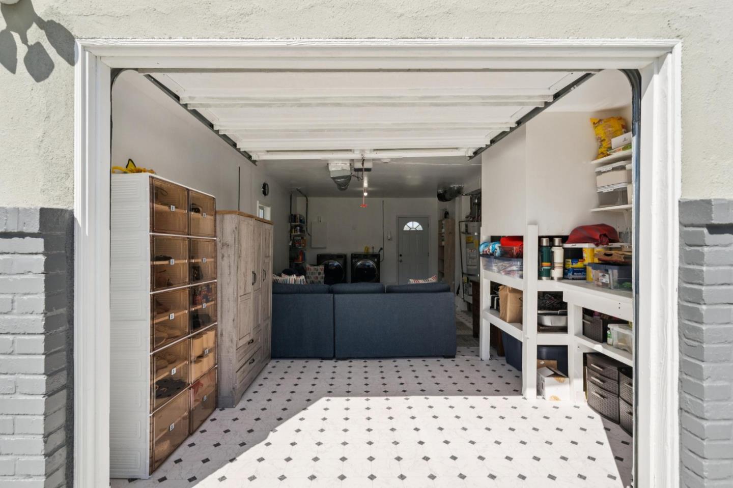 Garage with extensive storage cabinets and shelving, patterned tile floor, and washer and dryer.