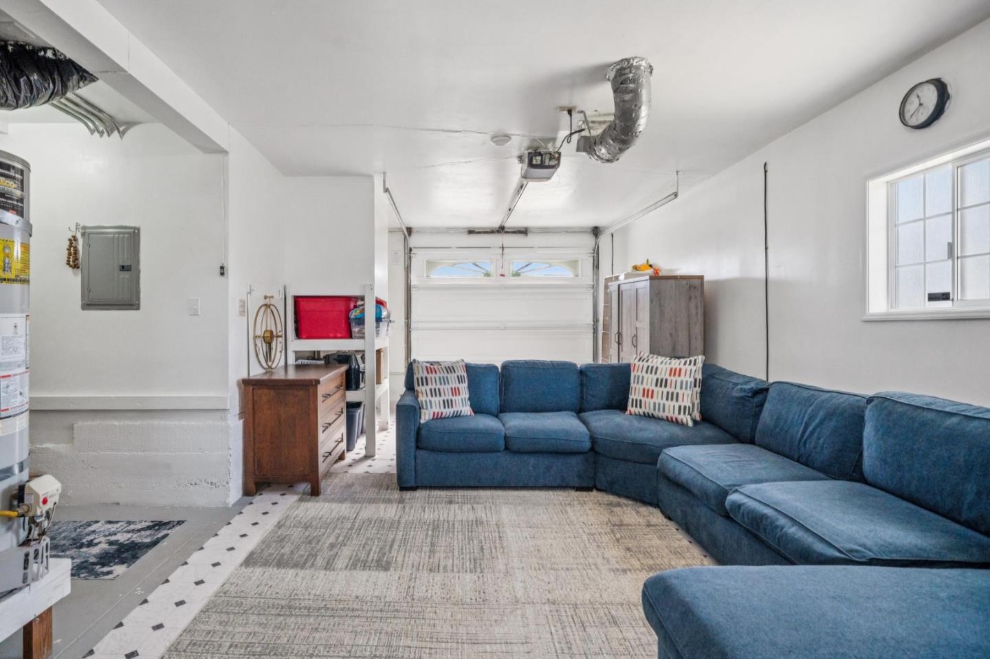 Garage furnished with a blue sectional sofa and rug, with the garage door behind it.