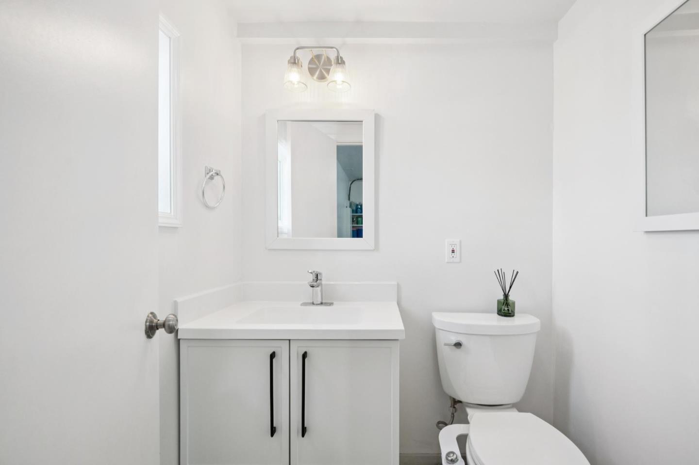 White bathroom with a vanity, framed mirror, and toilet.