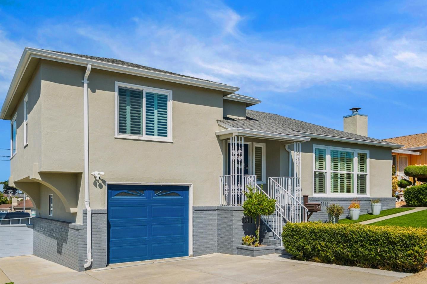 Two-story stucco home with a vivid blue garage door and white entry railings.