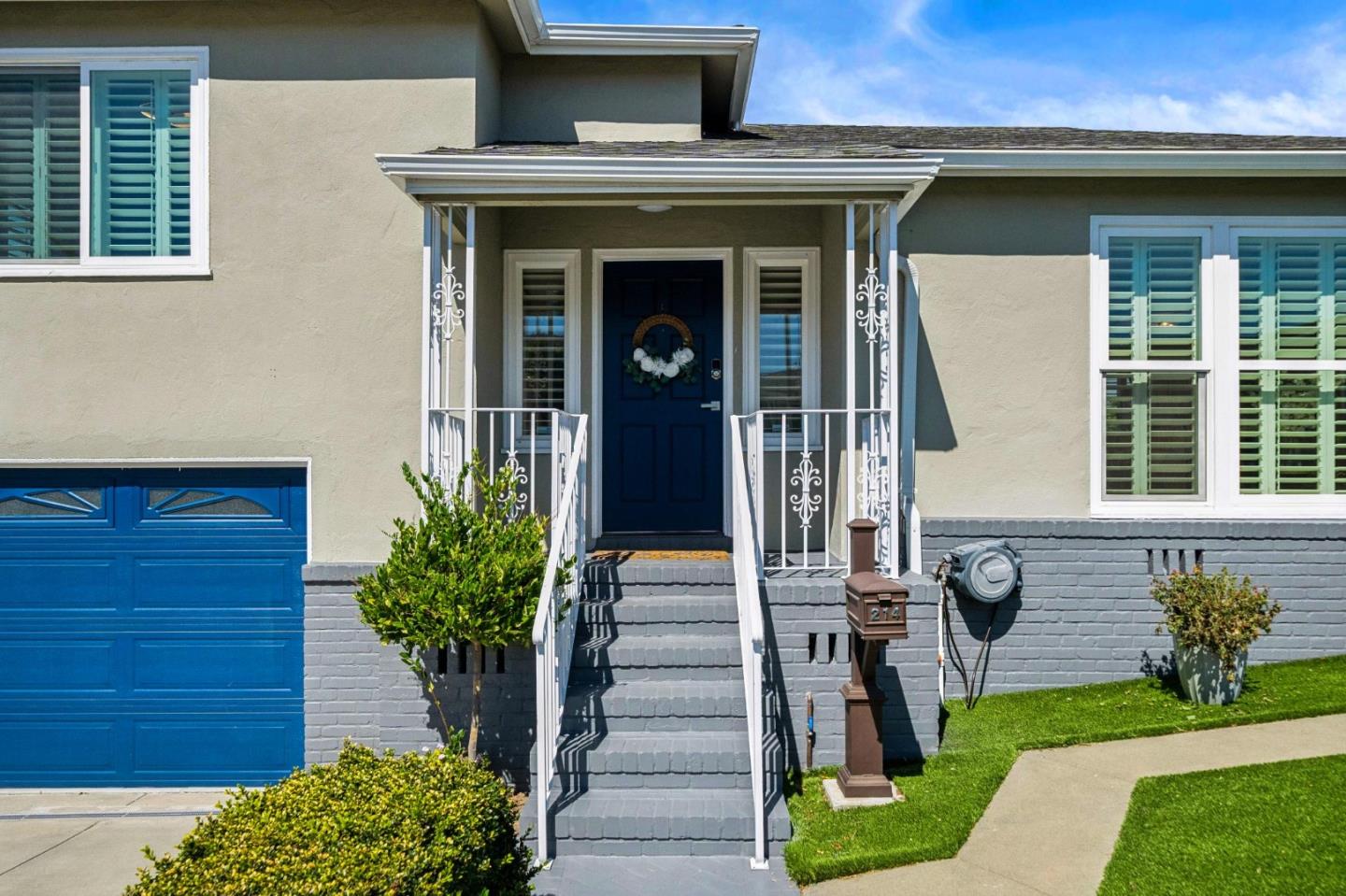 House exterior with blue garage door, gray front steps, white railings, and mailbox marked 214.
