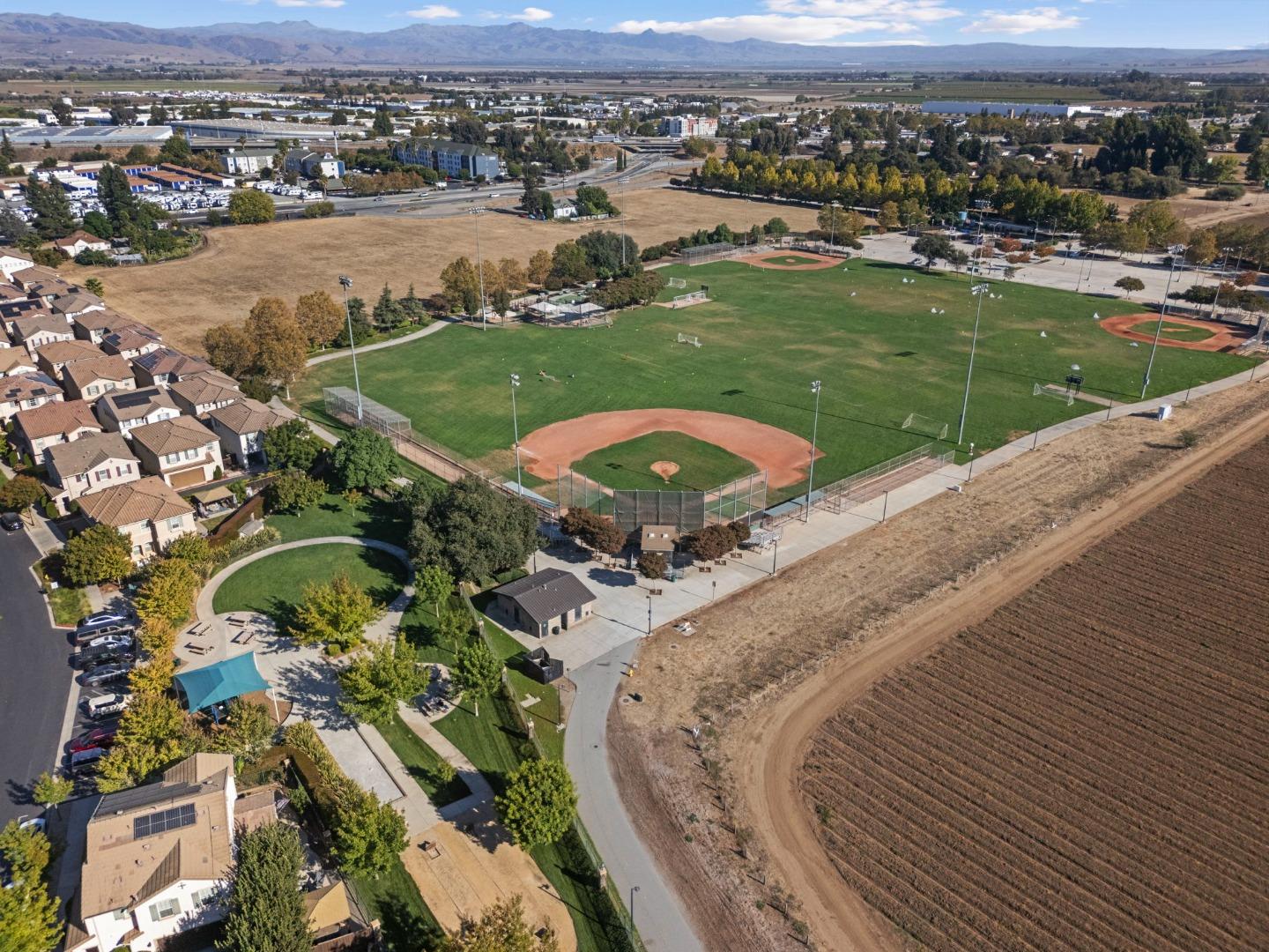 Aerial view of baseball fields and a soccer complex beside a Gilroy neighborhood and farmland.