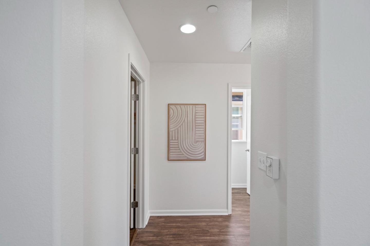 Bright hallway with dark wood floors and framed abstract art.