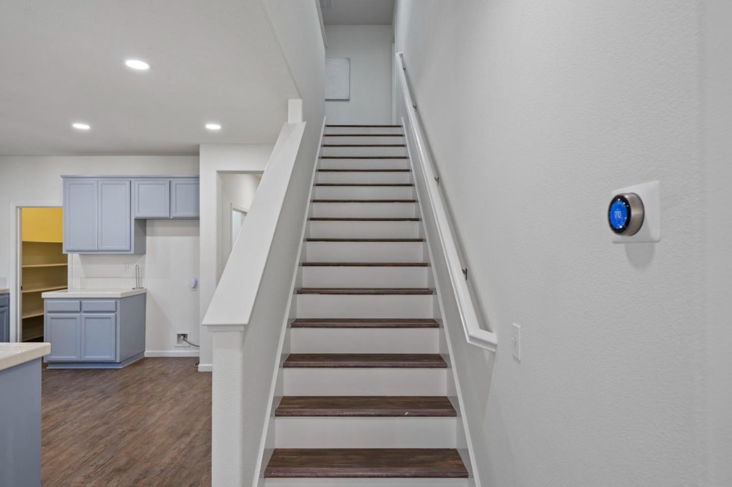 Staircase with dark wood treads and white railings beside blue-gray cabinetry.
