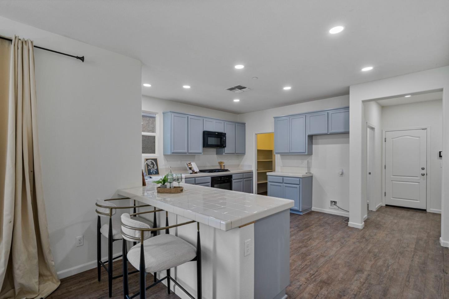 Kitchen with pale blue cabinets, a tiled breakfast bar, and wood-look flooring.