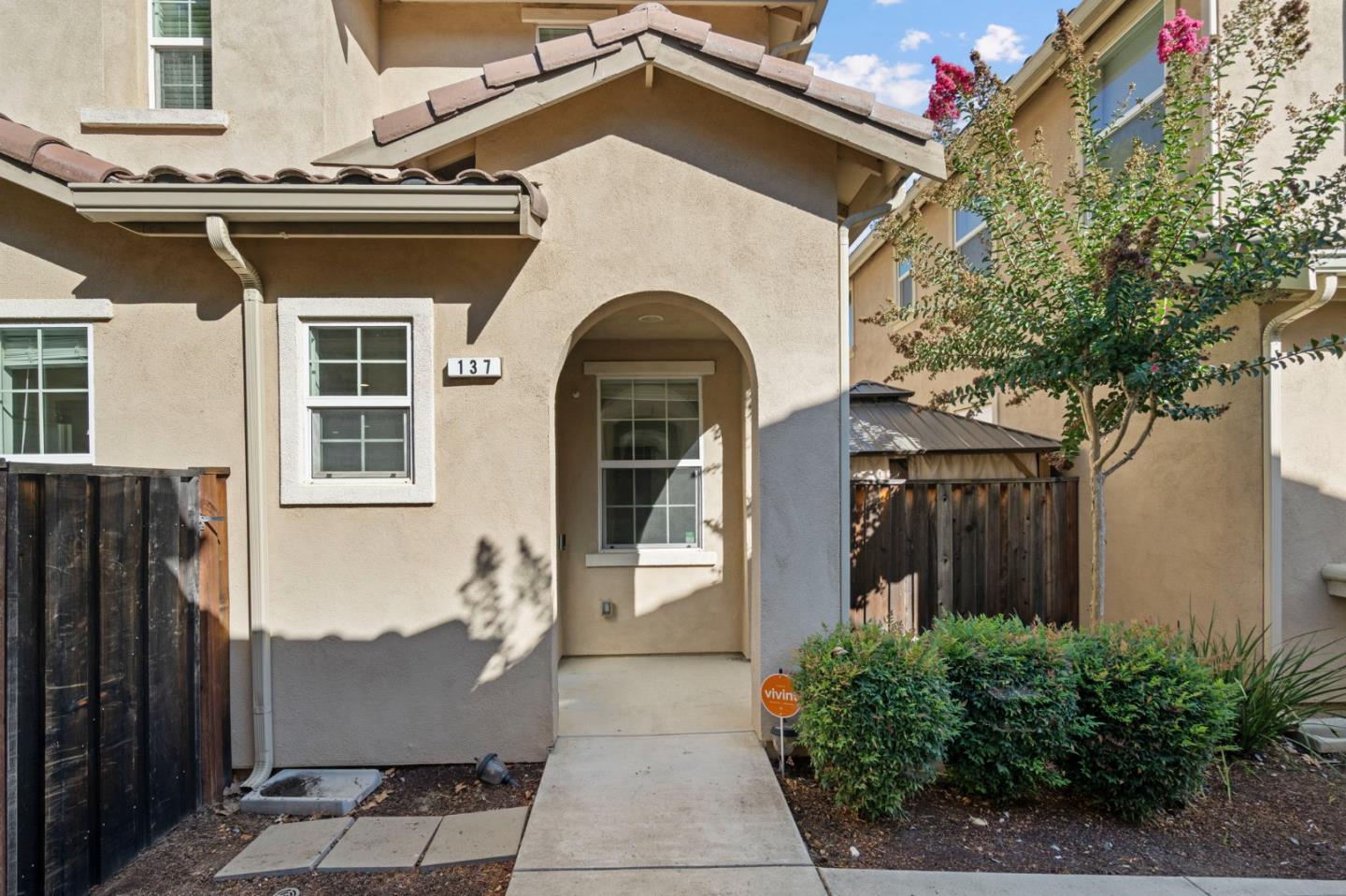 Home entrance with an arched recess, tiled roof, and concrete walkway.