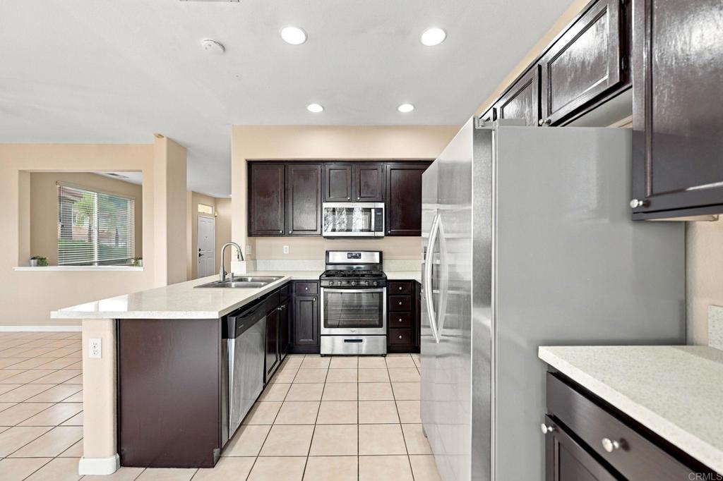 Kitchen with dark wood cabinets, stainless-steel appliances, and a white stone island with sink.