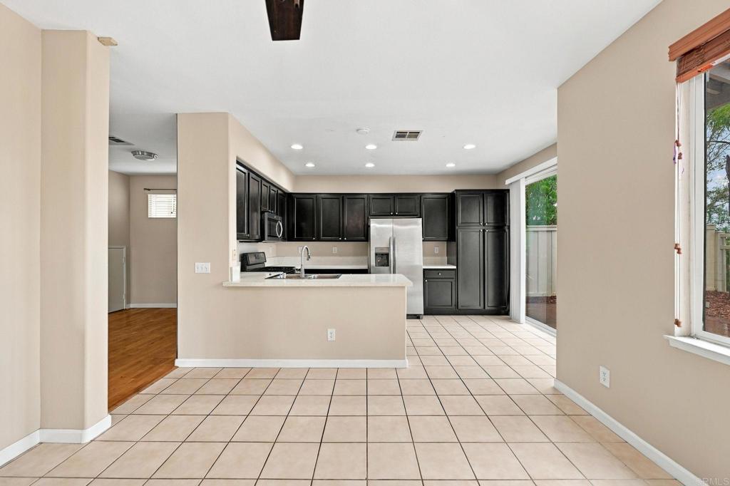 Open kitchen and dining area with dark cabinets, stainless steel appliances, and a peninsula breakfast bar.