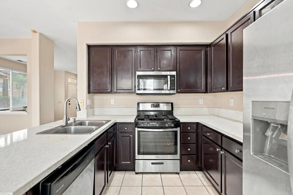 Kitchen with dark wood cabinets, light countertops, and stainless steel appliances.