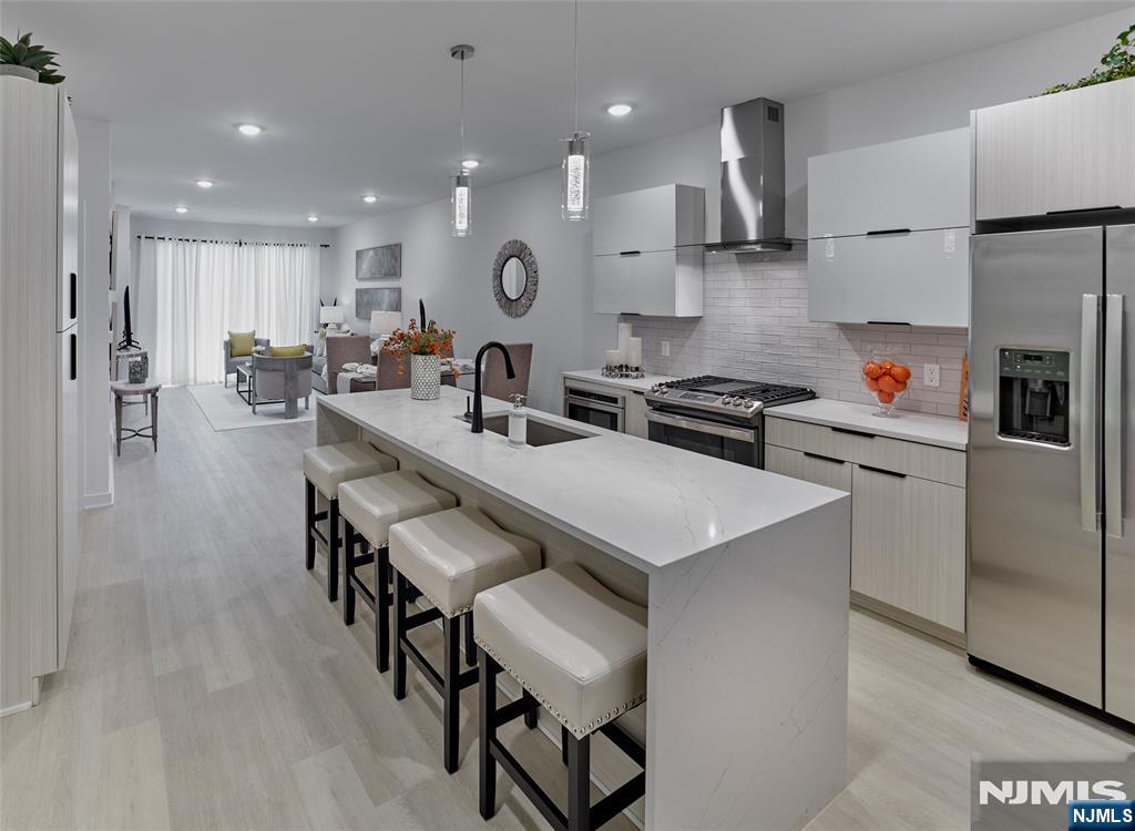Modern kitchen with a long island and four stools, opening into a furnished living area.
