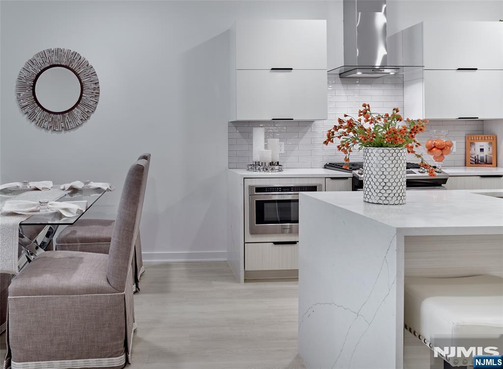 Open-plan kitchen and dining area with white cabinetry, marble-look island, and glass dining table.