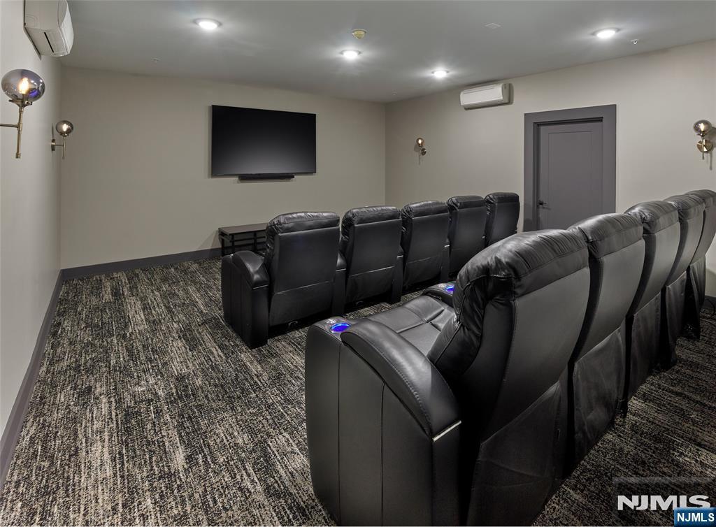 Home theater with two rows of black leather recliners facing a wall-mounted screen.