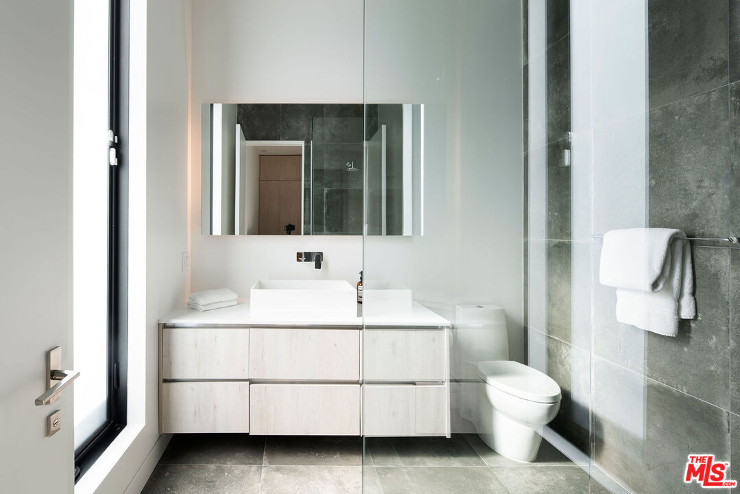 Modern bathroom with a floating vanity, glass shower enclosure, and wall-mounted toilet.