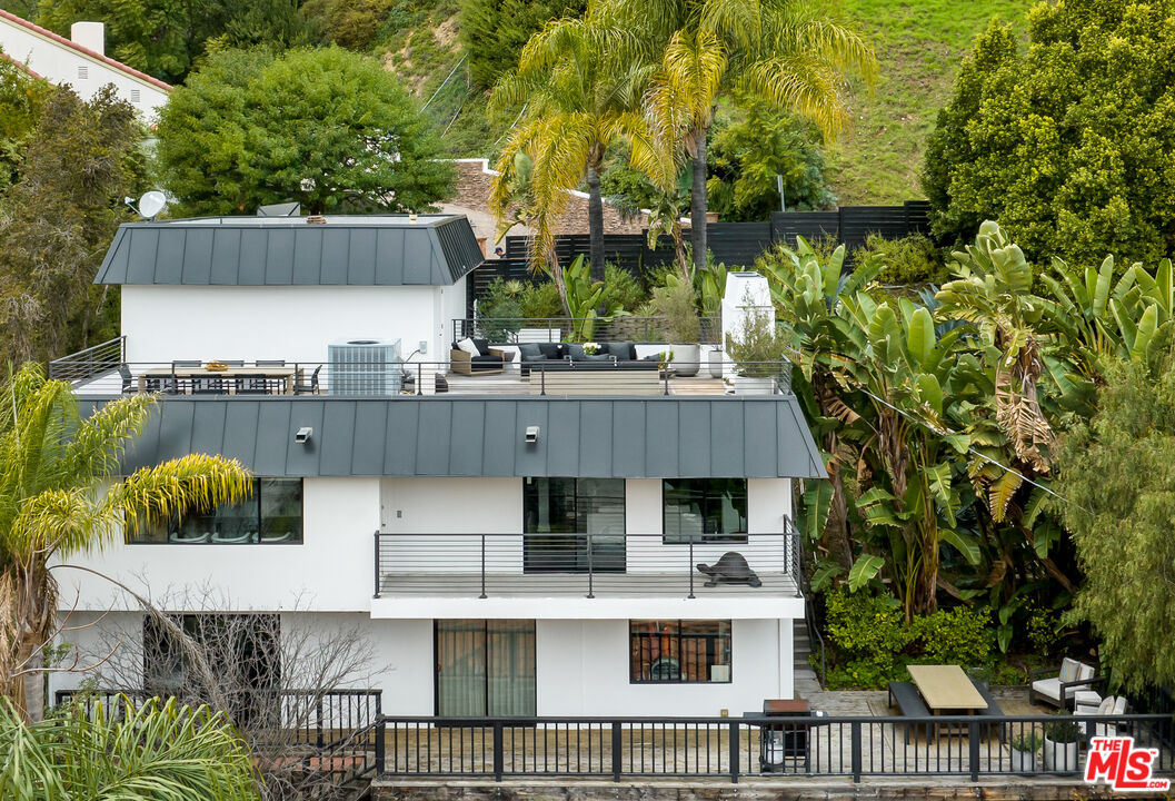 Modern multi-level home with broad terraces and tropical landscaping on a hillside.