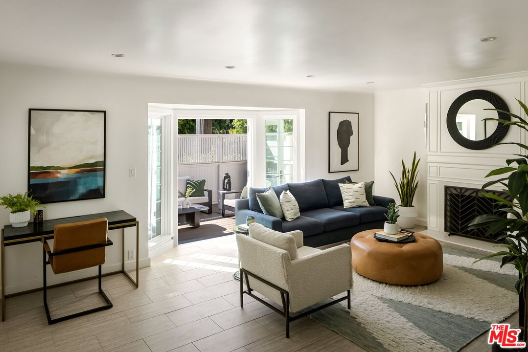 Living room with a navy sofa, white fireplace, and open doors to a private patio.