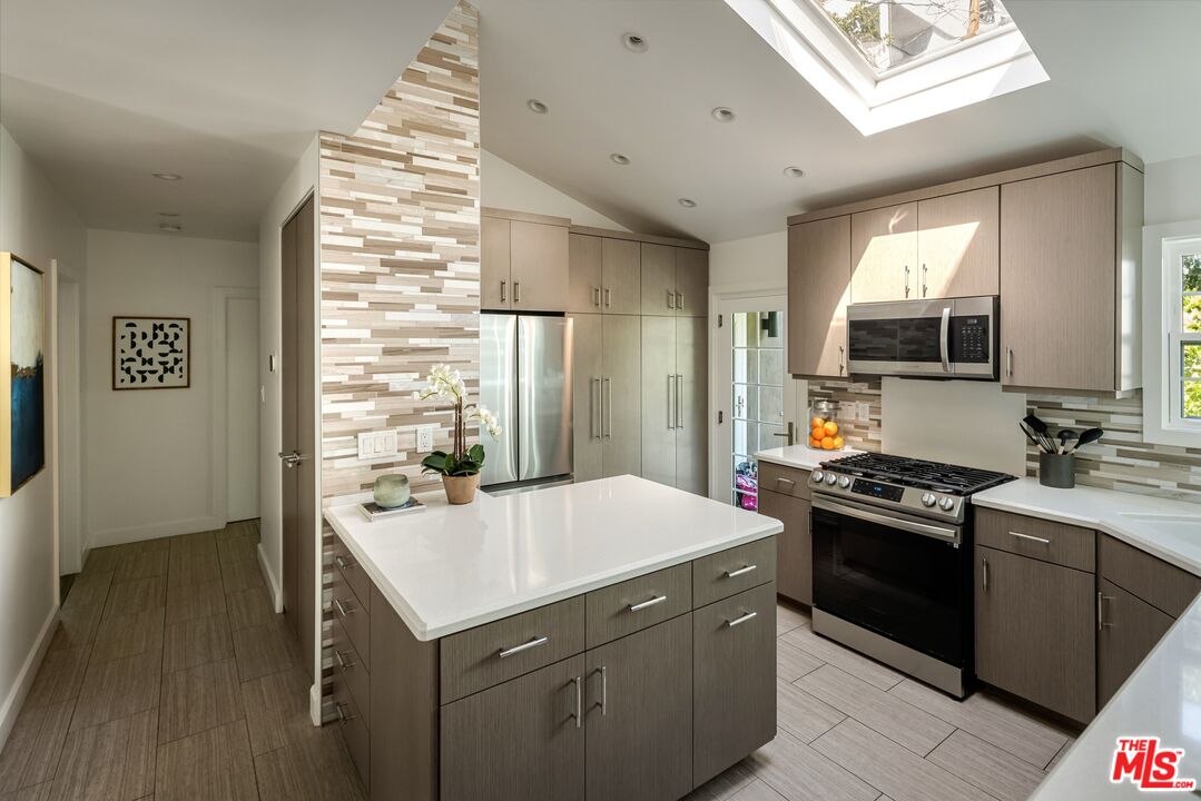 Kitchen with a large island, stainless steel appliances, and a skylight.