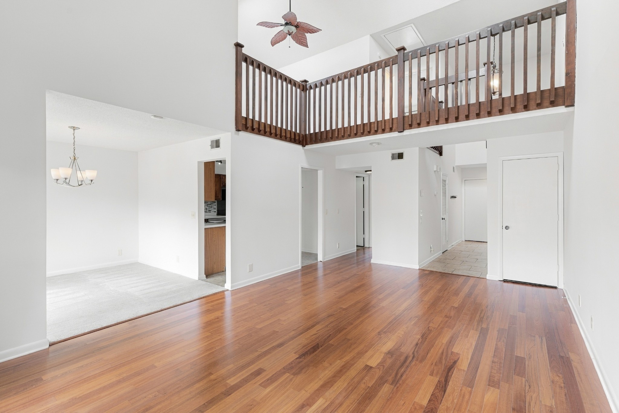 Open living area with hardwood floors and a wooden loft railing above.