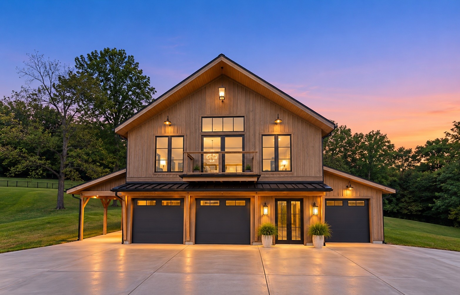 Wood-sided two-story home with three garage doors and a small balcony, illuminated at dusk.