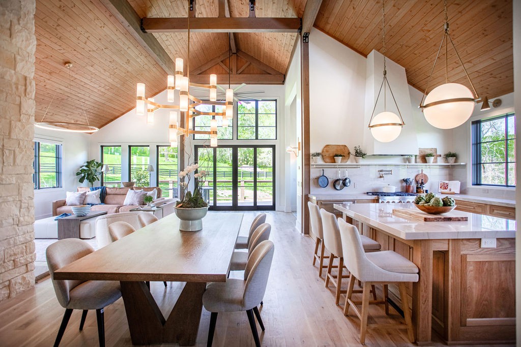 Open-plan kitchen and dining room with a large island beneath a vaulted wood ceiling.