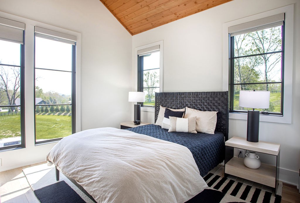 Bedroom with navy and white bedding, a woven headboard, and vaulted wood ceiling.