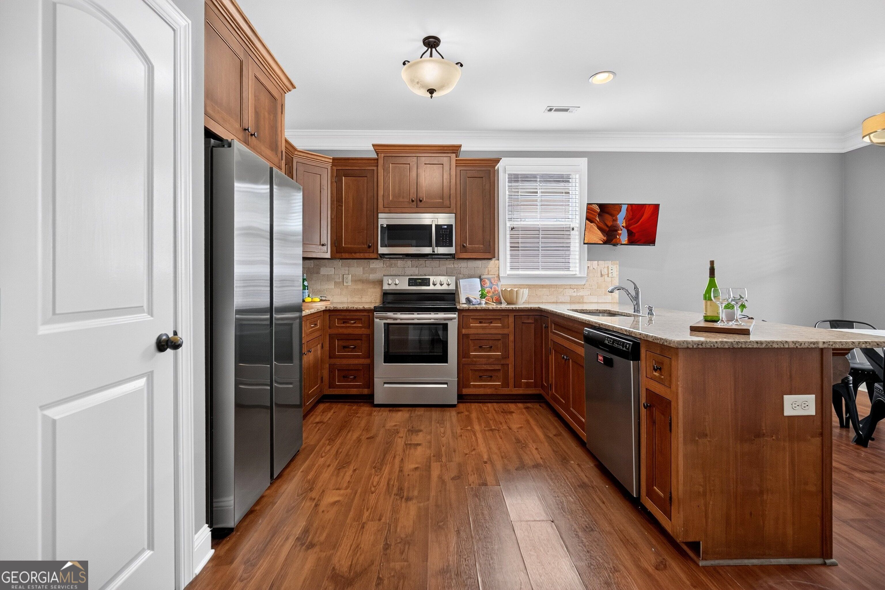 Kitchen with warm wood cabinetry, stainless steel appliances, and a stone-topped peninsula.