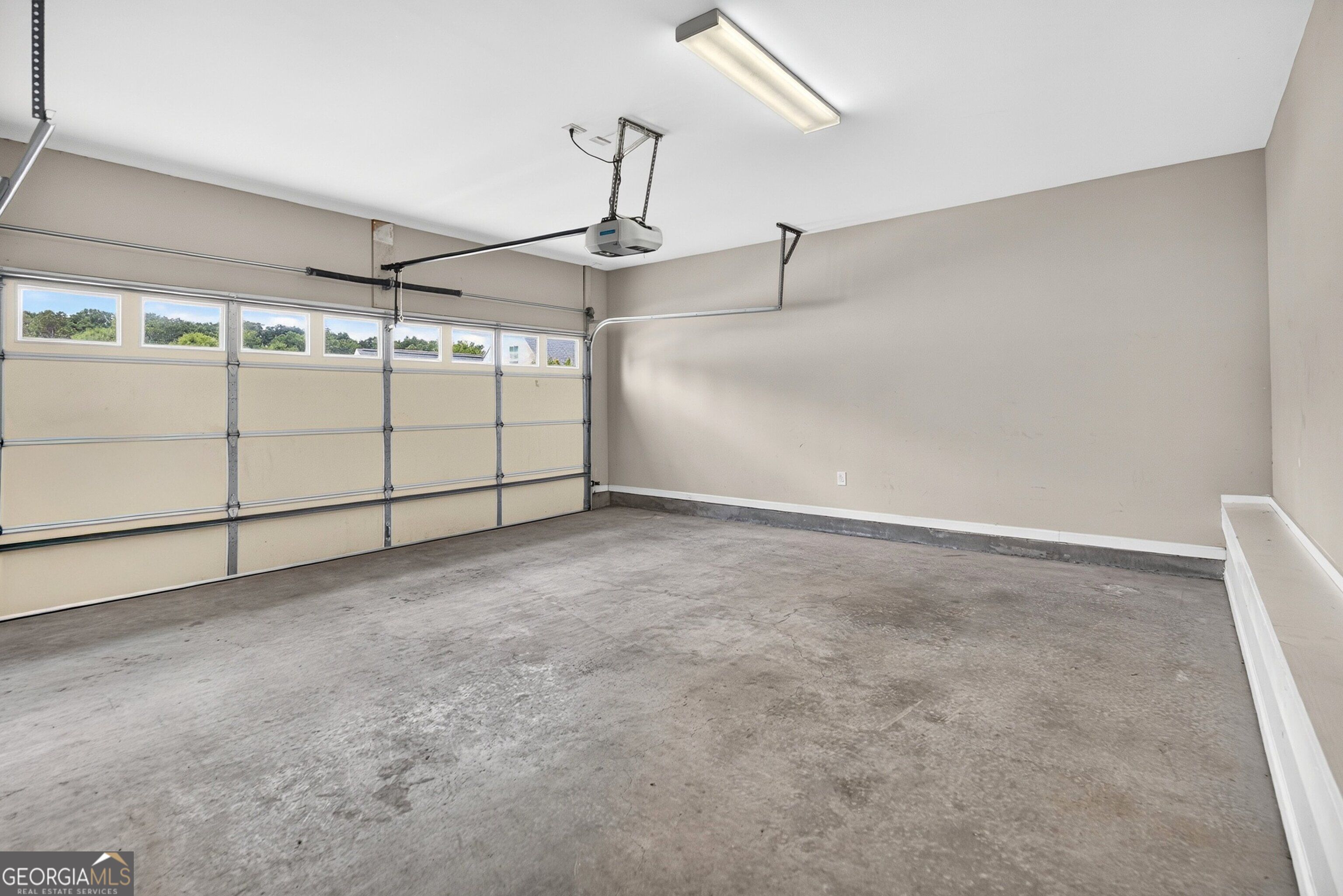 Empty garage with a concrete floor and closed sectional door with windows.
