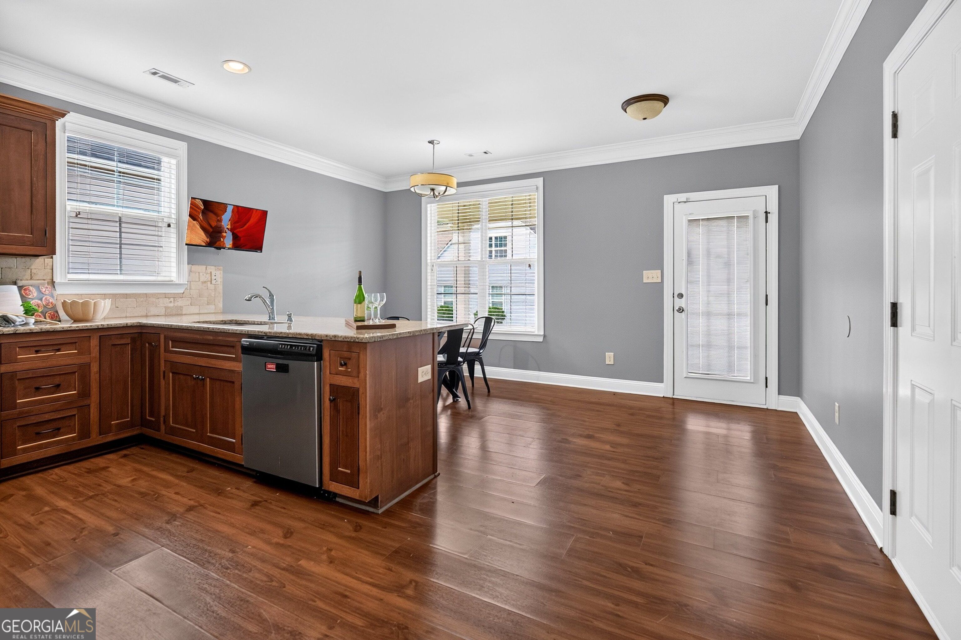 Kitchen with a wood island, dishwasher, hardwood floors, and a dining area by the windows.