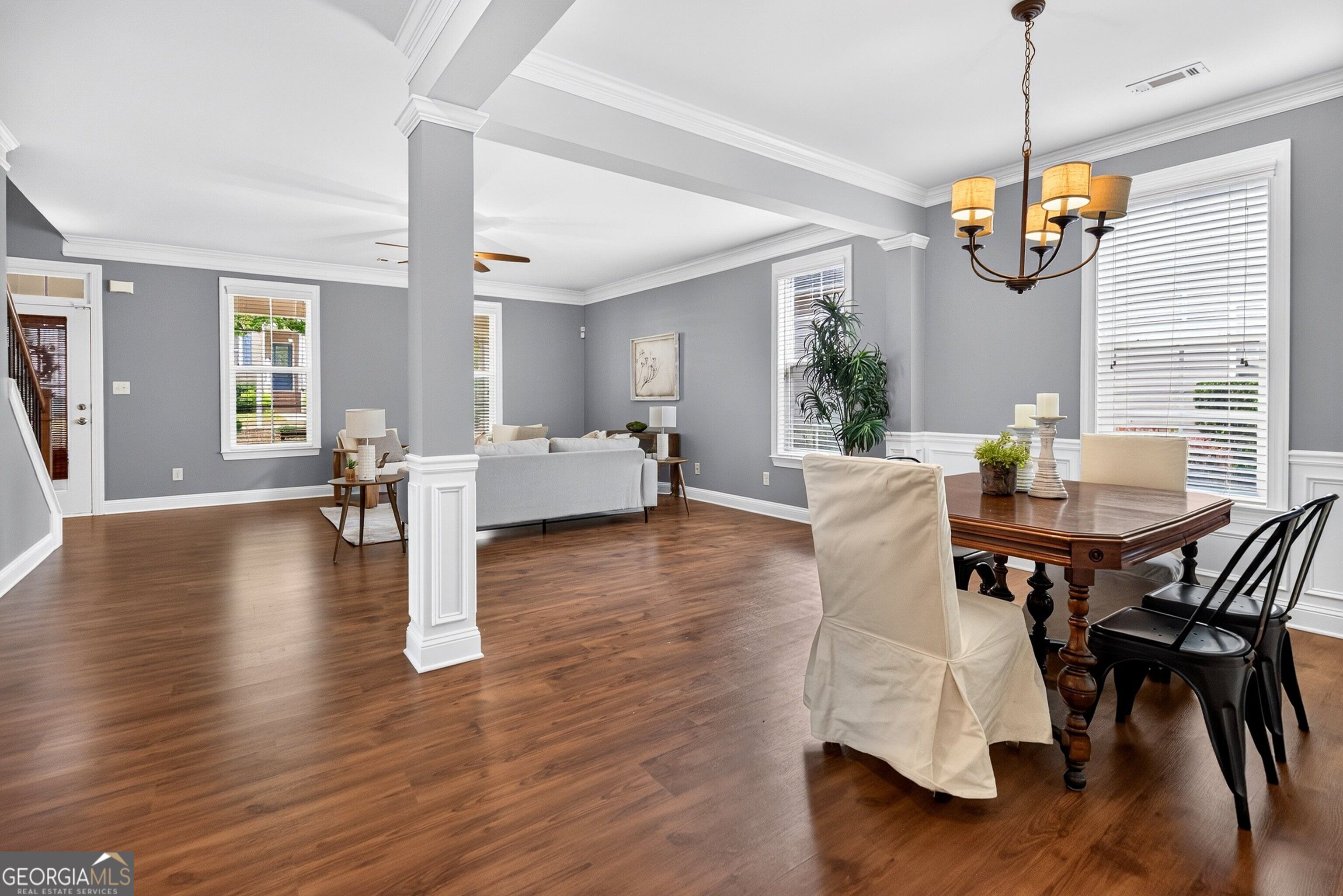 Open-plan living and dining room with hardwood floors, gray walls, white trim, and a central column.