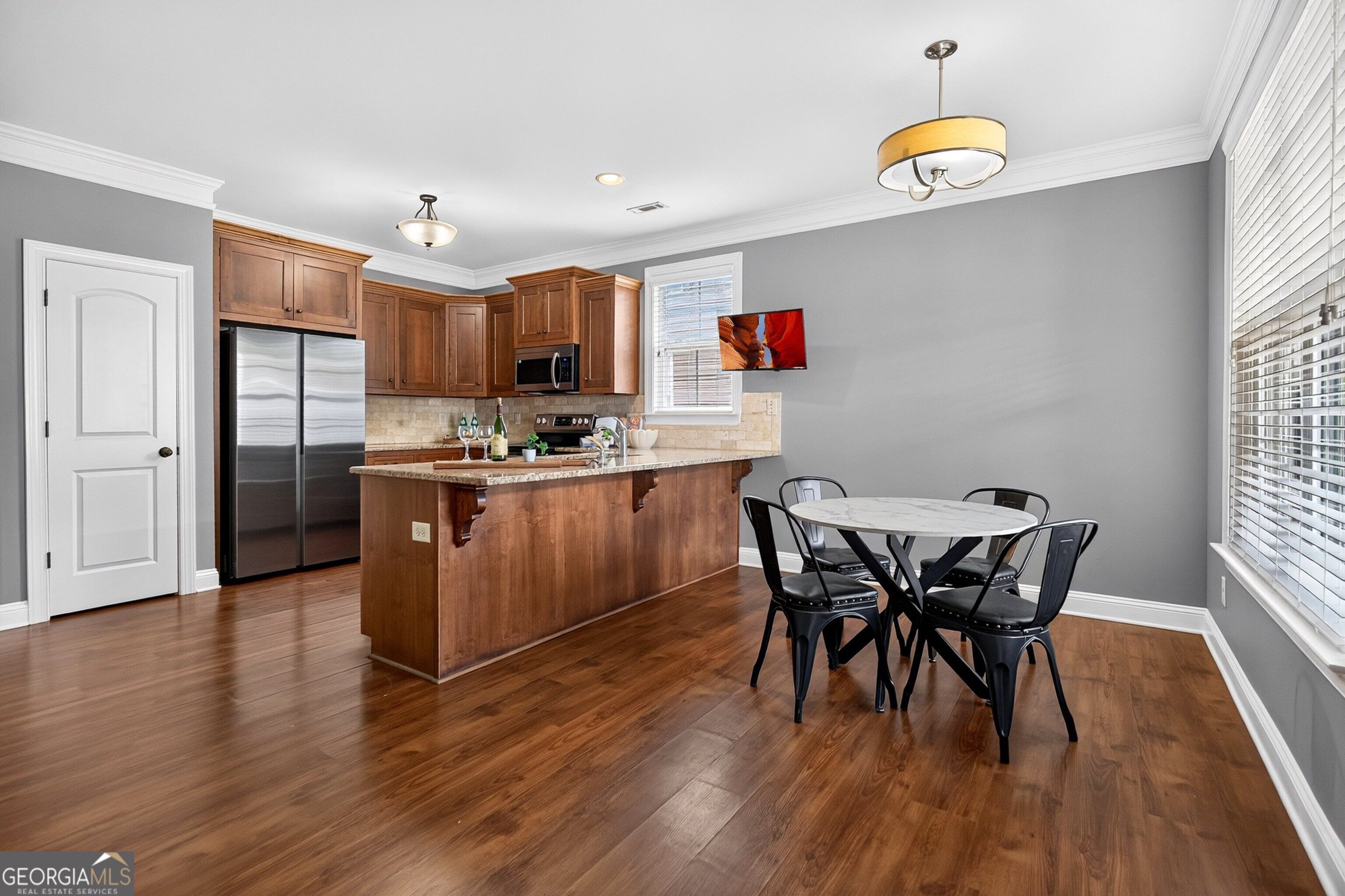 Kitchen and dining area with wood cabinetry, stainless appliances, breakfast bar, and round table.