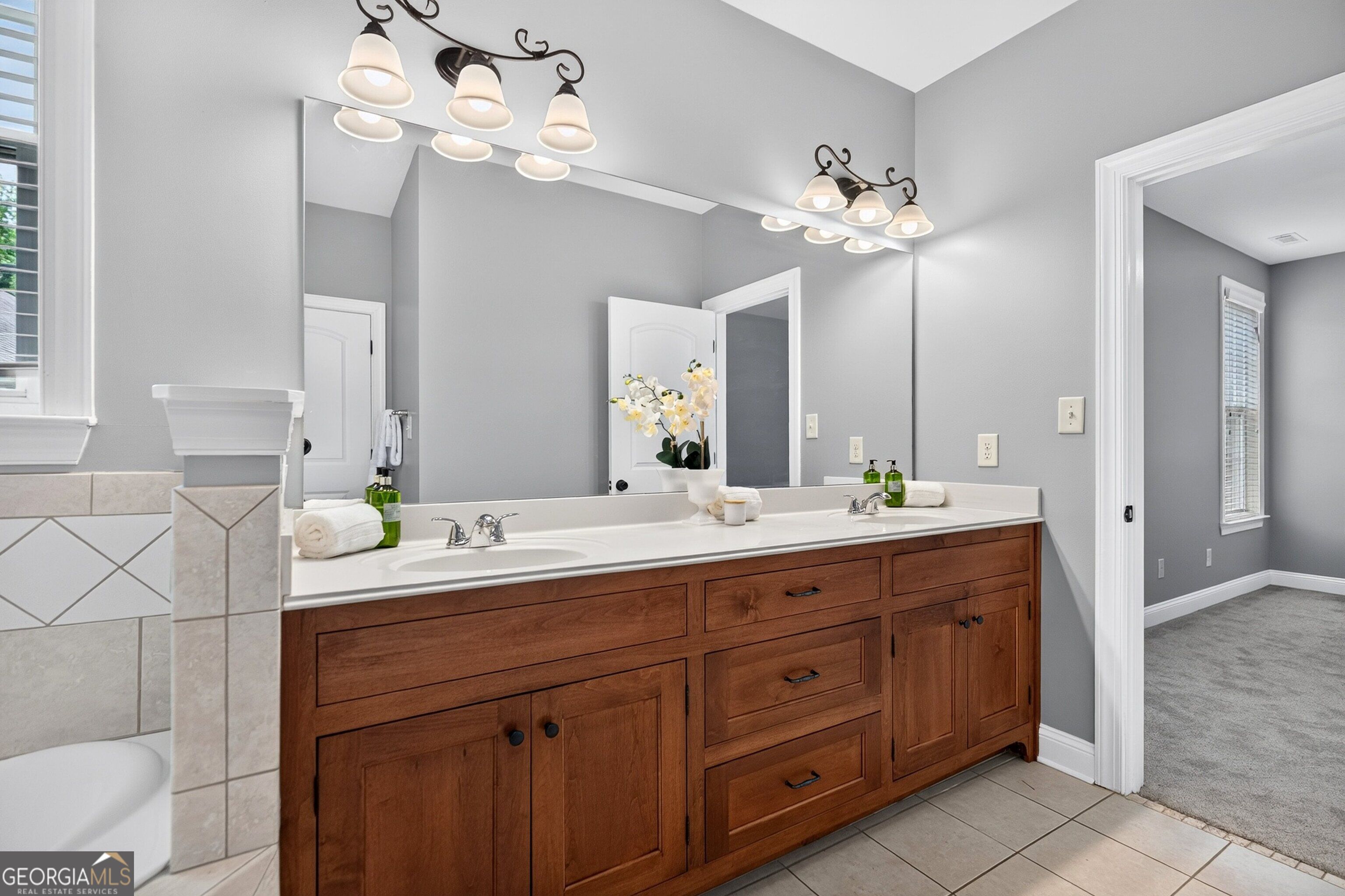 Bathroom with a long cherry-wood vanity, white countertop, and large mirror.