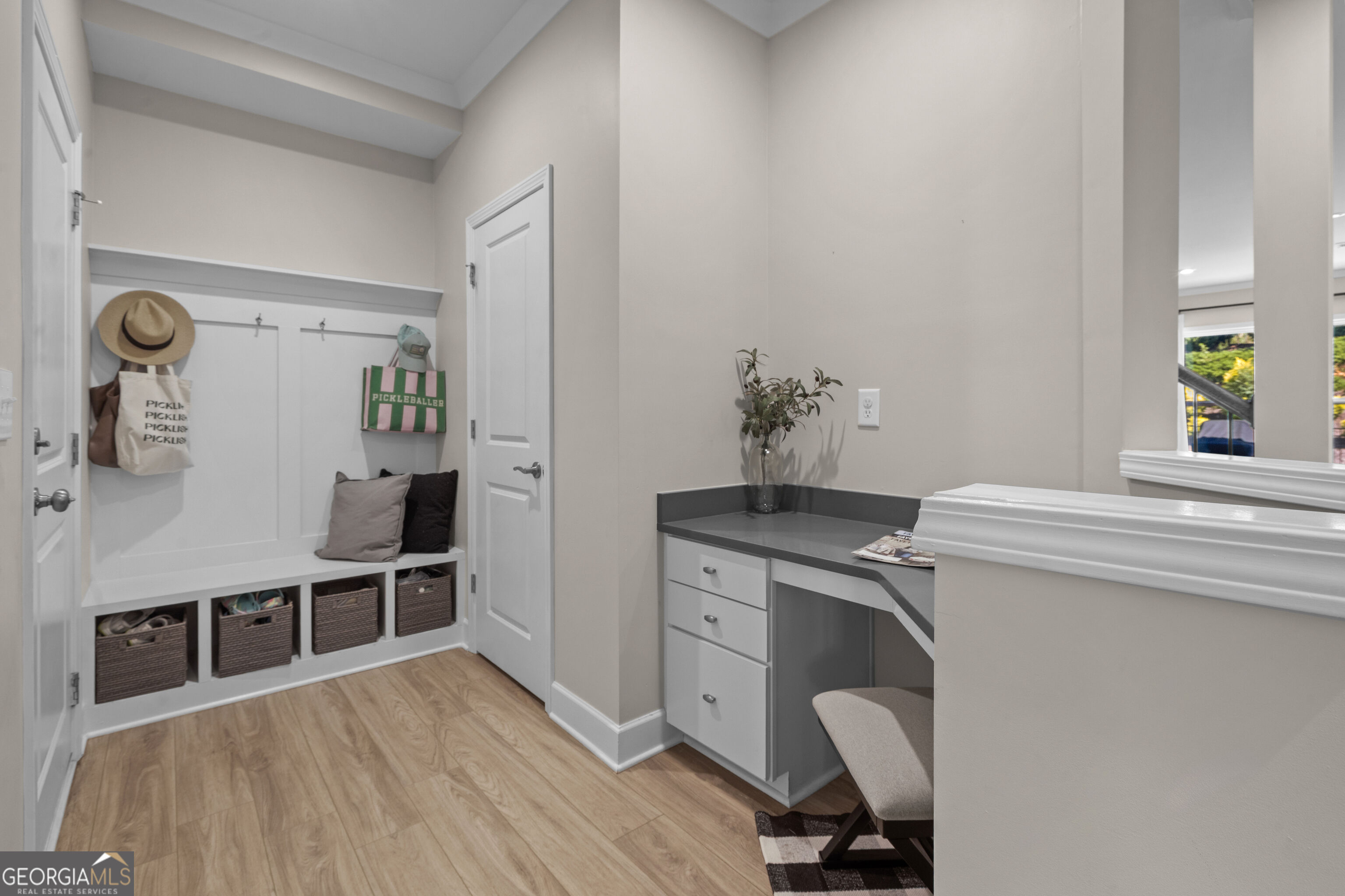 Mudroom with a built-in bench, hanging bags, woven baskets, and a compact desk nook.