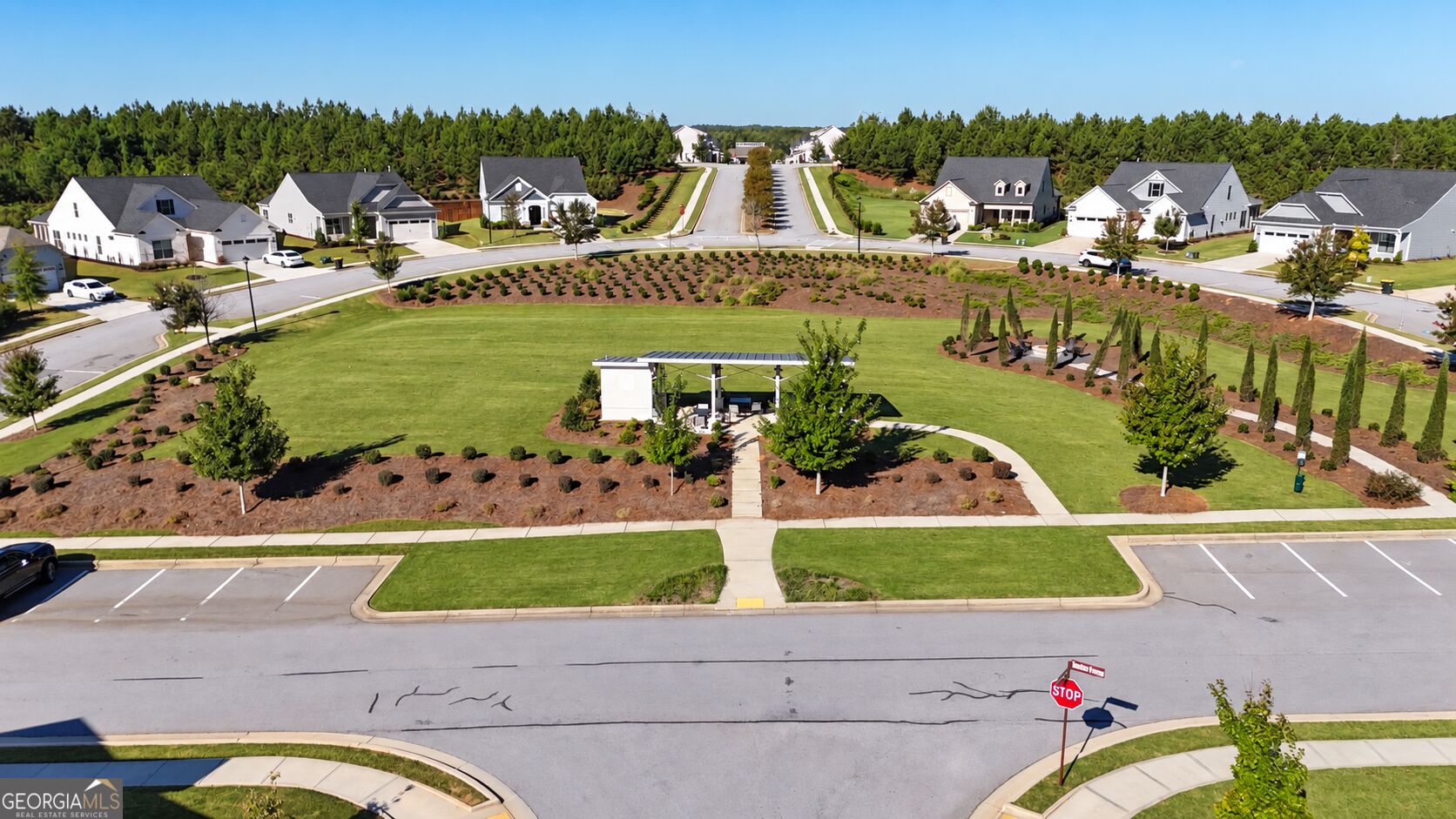 Aerial view of a neighborhood green with a gazebo, walking paths, and surrounding homes.