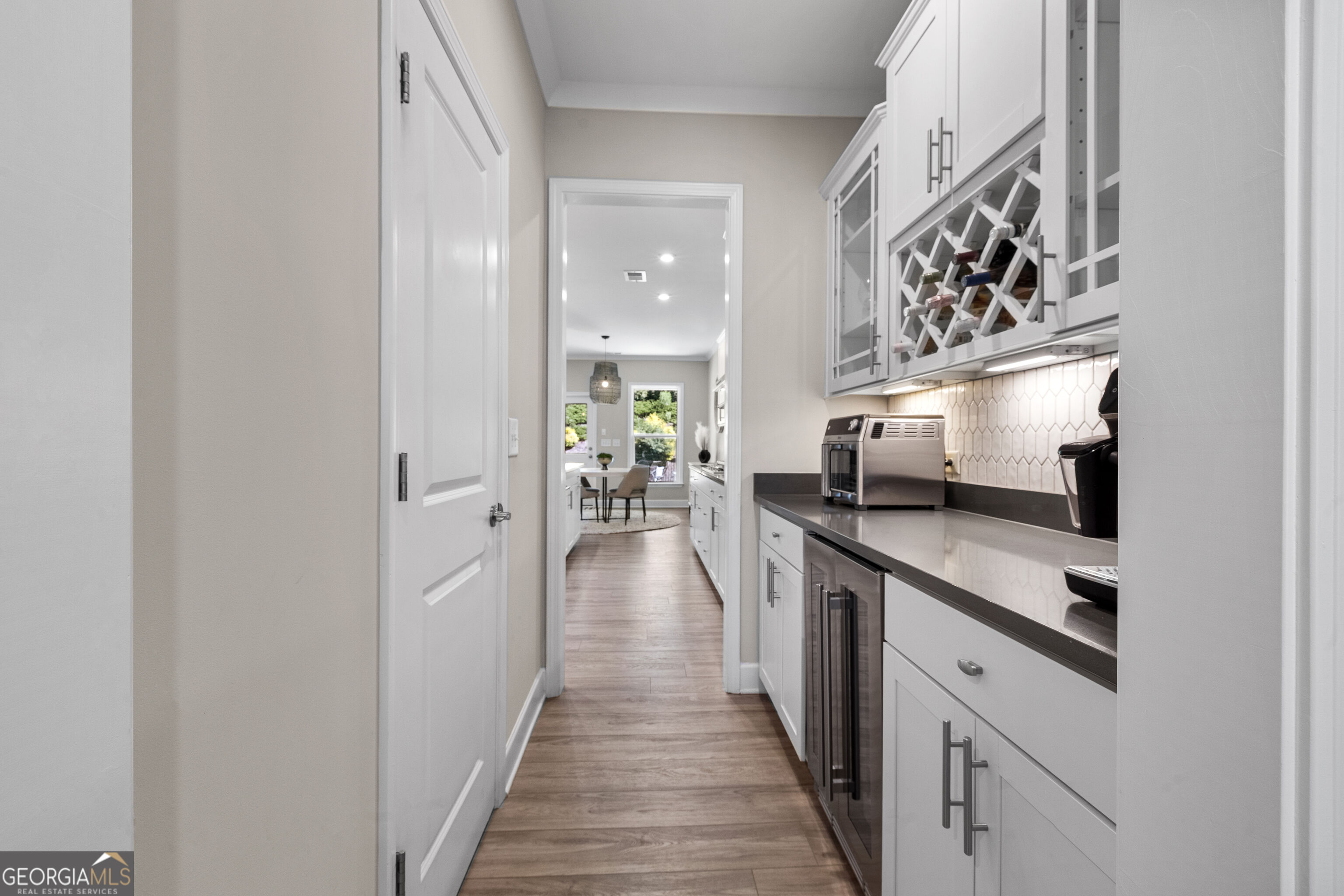Kitchen with built-in wine rack, beverage refrigerators, and a view through to the dining area.
