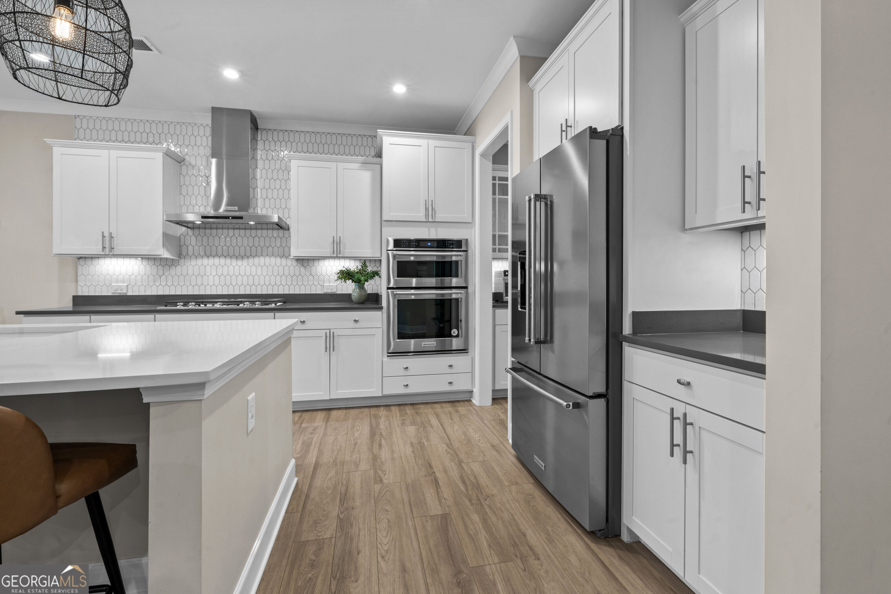 Modern kitchen with white cabinetry, stainless steel appliances, geometric tile backsplash, and a large island.