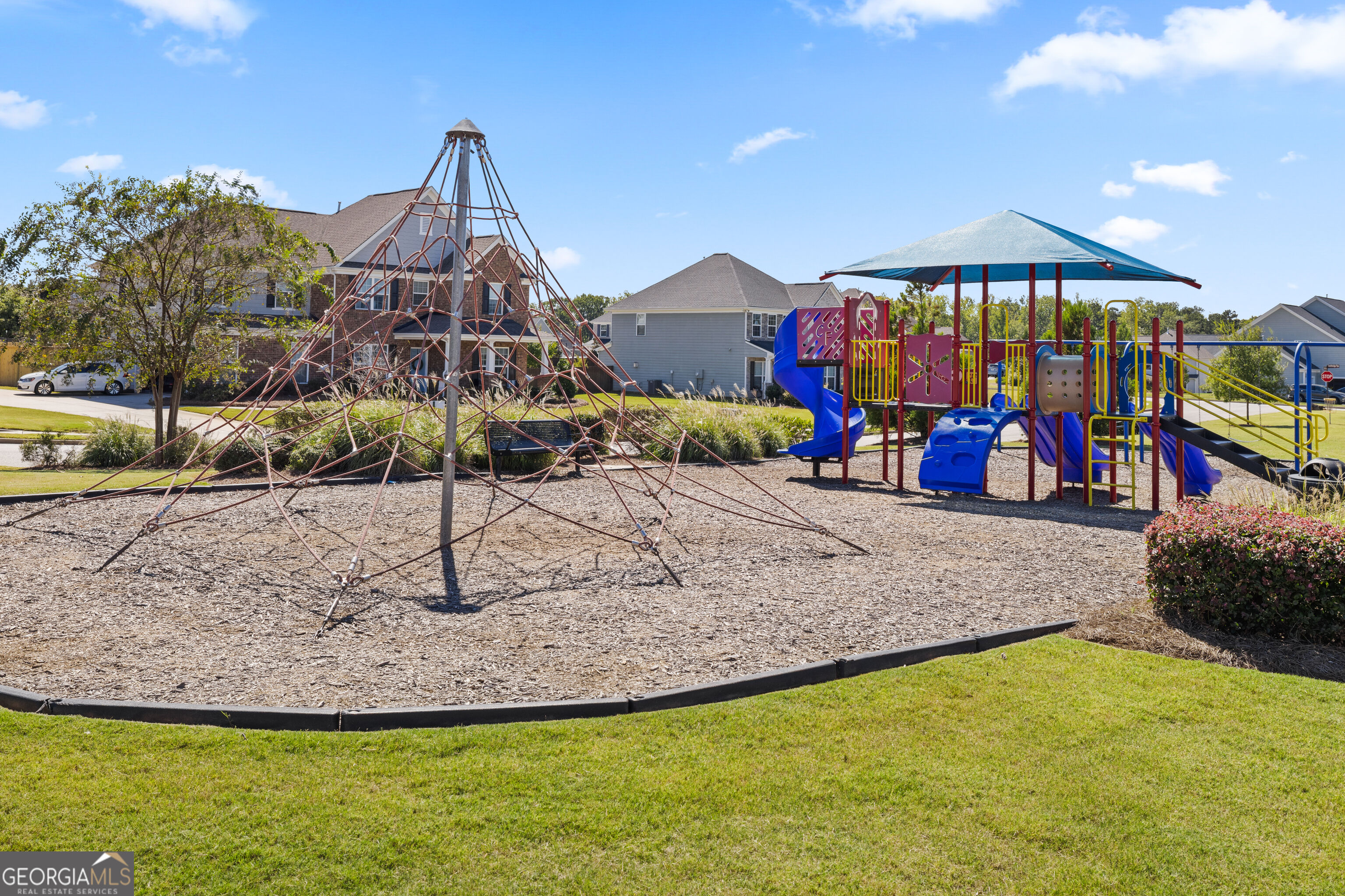 Neighborhood playground with colorful slides and a large rope climbing pyramid.