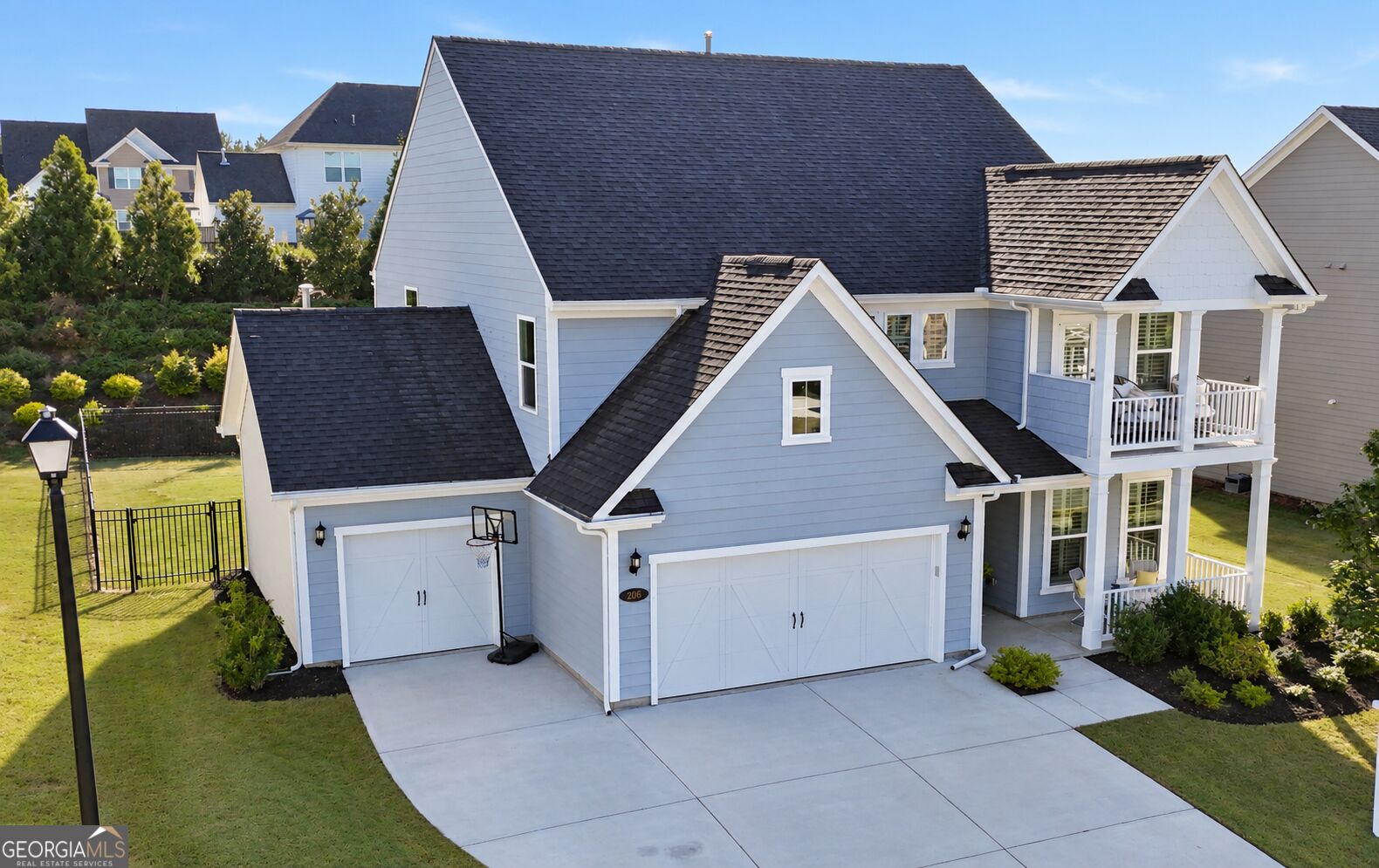 Blue-gray two-story house with two garages, covered porches, and a basketball hoop beside the driveway.
