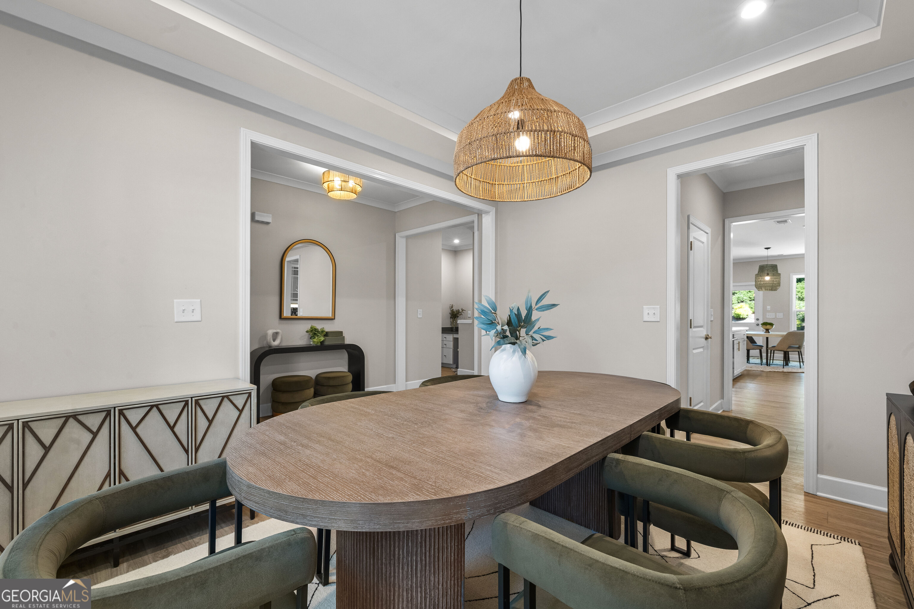 Dining room with an oval wood table, olive-green chairs, and a woven pendant light.