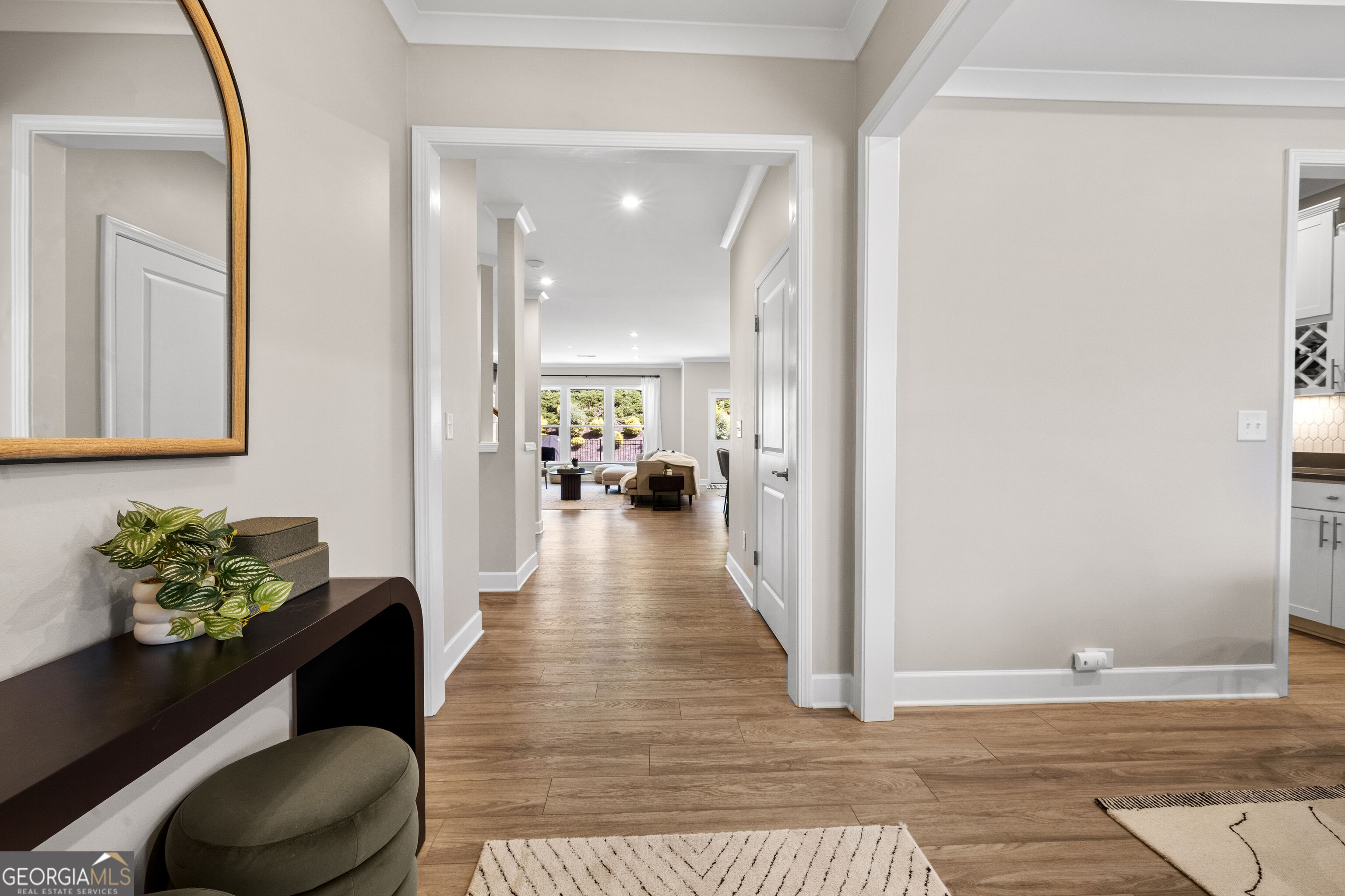 Furnished entry hall with warm wood floors leading toward a bright living room.