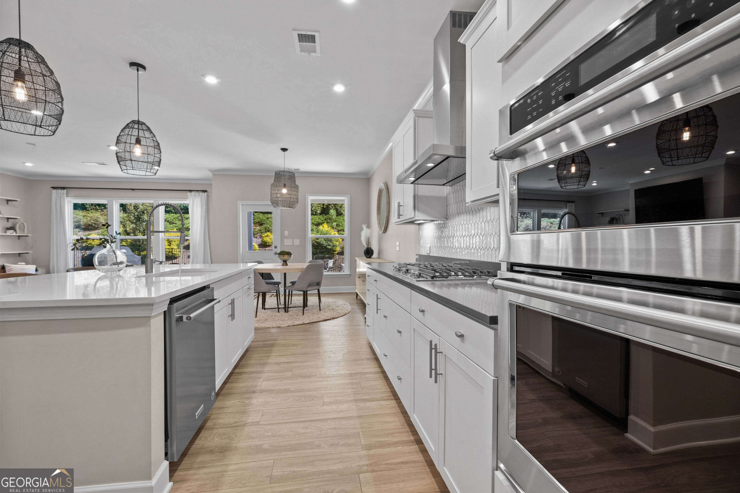 Kitchen with a large white island, stainless-steel range, patterned backsplash, and adjoining dining nook.