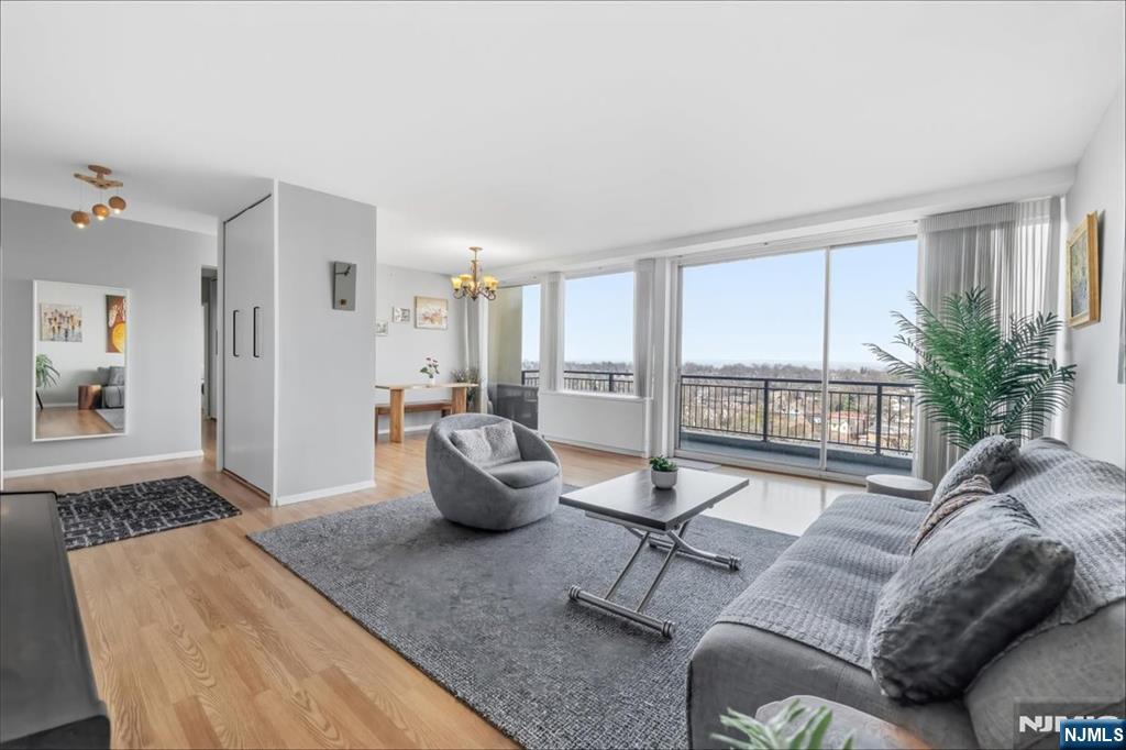 Living room with gray seating, wood floors, and broad windows opening onto a balcony.